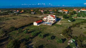 An aerial view of a residential area with houses, a swimming pool, and a large building with a red roof. - Villa Roko Zadarvillas (Škabrnja)
