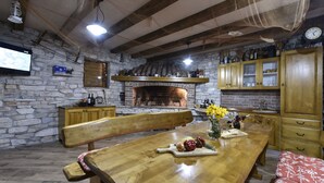A rustic kitchen with a stone wall, wooden beams, a brick fireplace, and wooden cabinets. - Villa Roko Zadarvillas (Škabrnja)