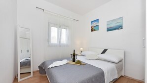 A modern bedroom with a bed, a bedside table with a bottle and glasses, a mirror, and two paintings on the wall. - Villa Roko Zadarvillas (Škabrnja)