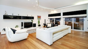 Un salon moderne avec un canapé blanc, un téléviseur à écran plat et une grande fenêtre.