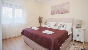 A bedroom with a bed, bedside tables, a chandelier, a window with curtains, and a painting on the wall. - Villa Olive Zadarvillas (Policnik)