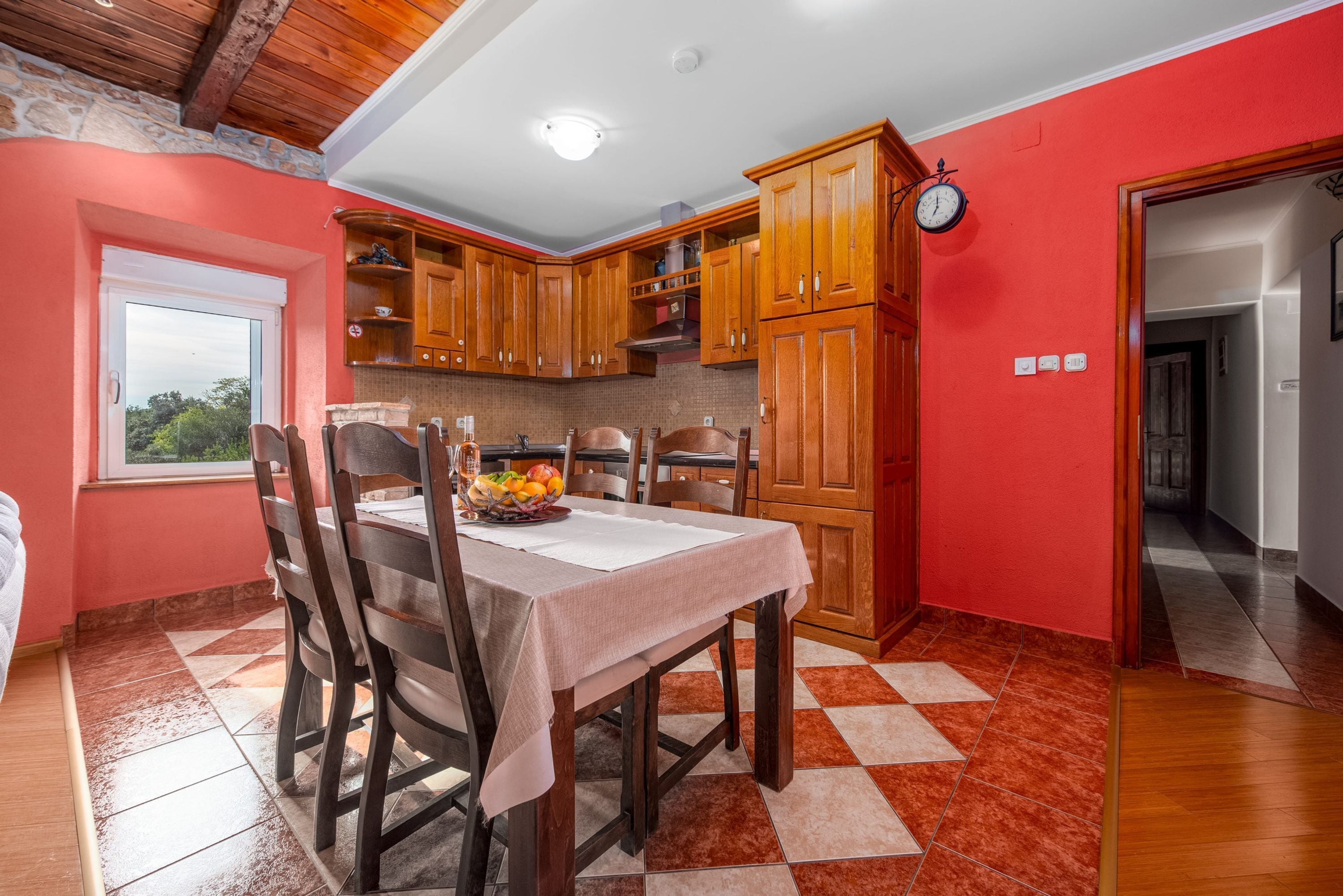 Una cocina con armarios de madera, una mesa de comedor con sillas y un frutero.