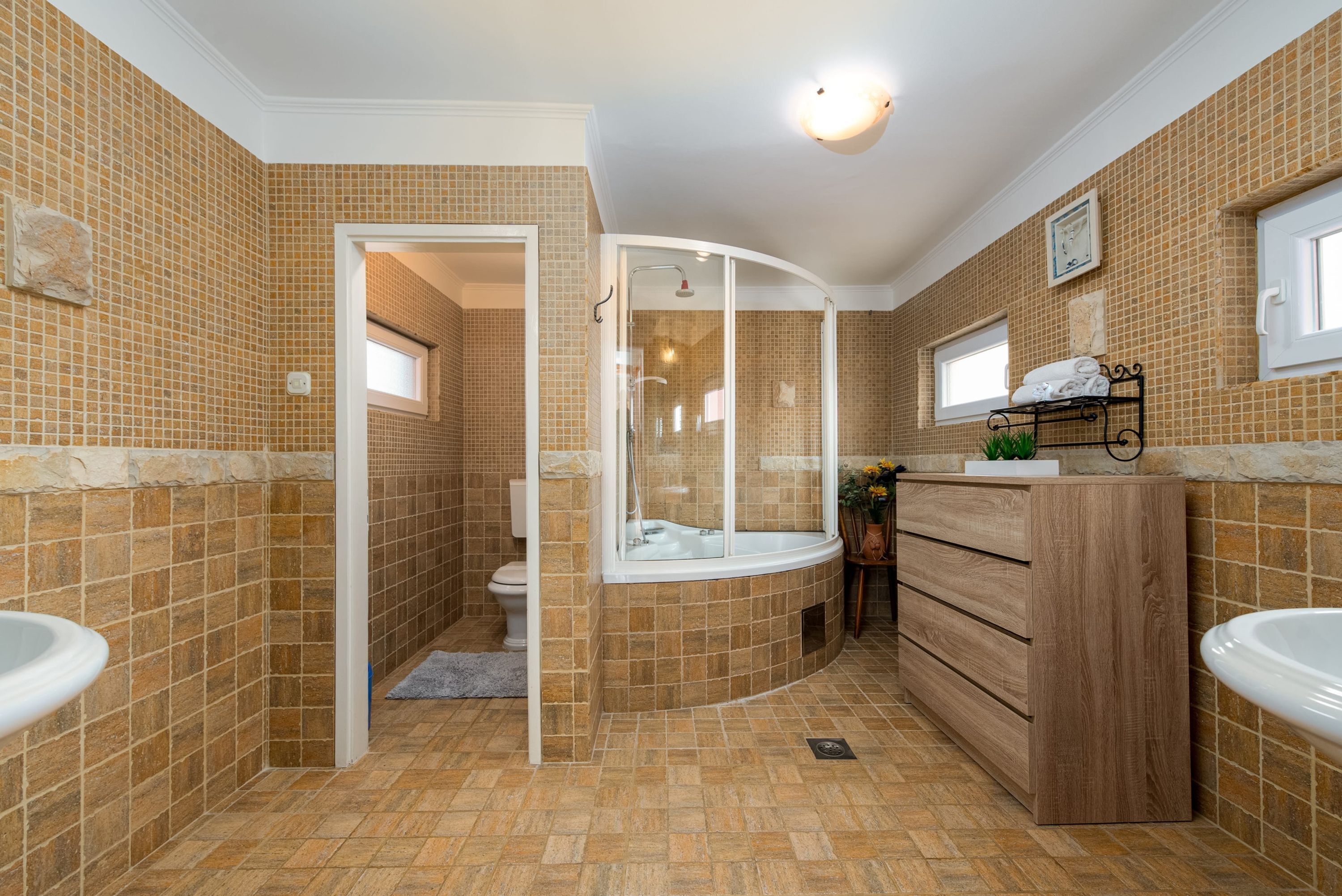 A bathroom with a curved bathtub, a glass-enclosed shower, and a wooden vanity with a sink.