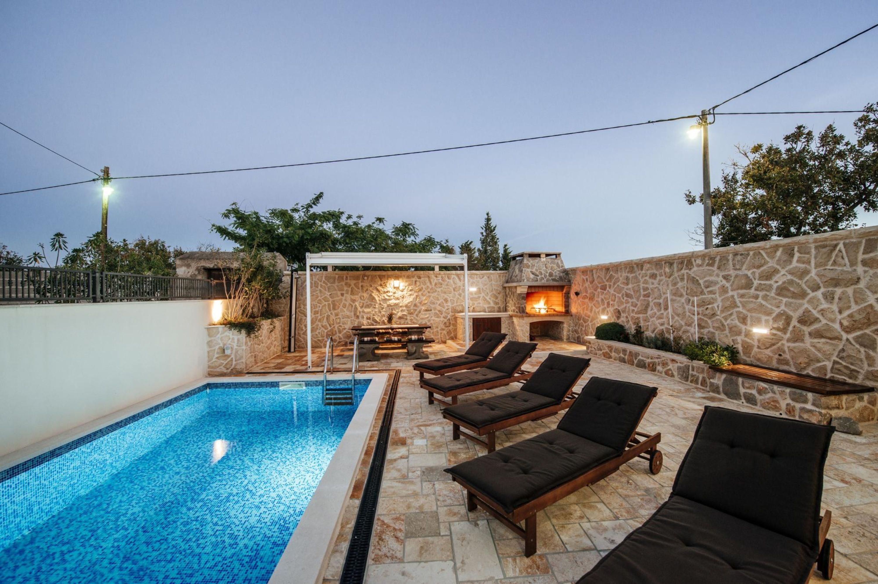 Une piscine avec des chaises longues et un mur en pierre.