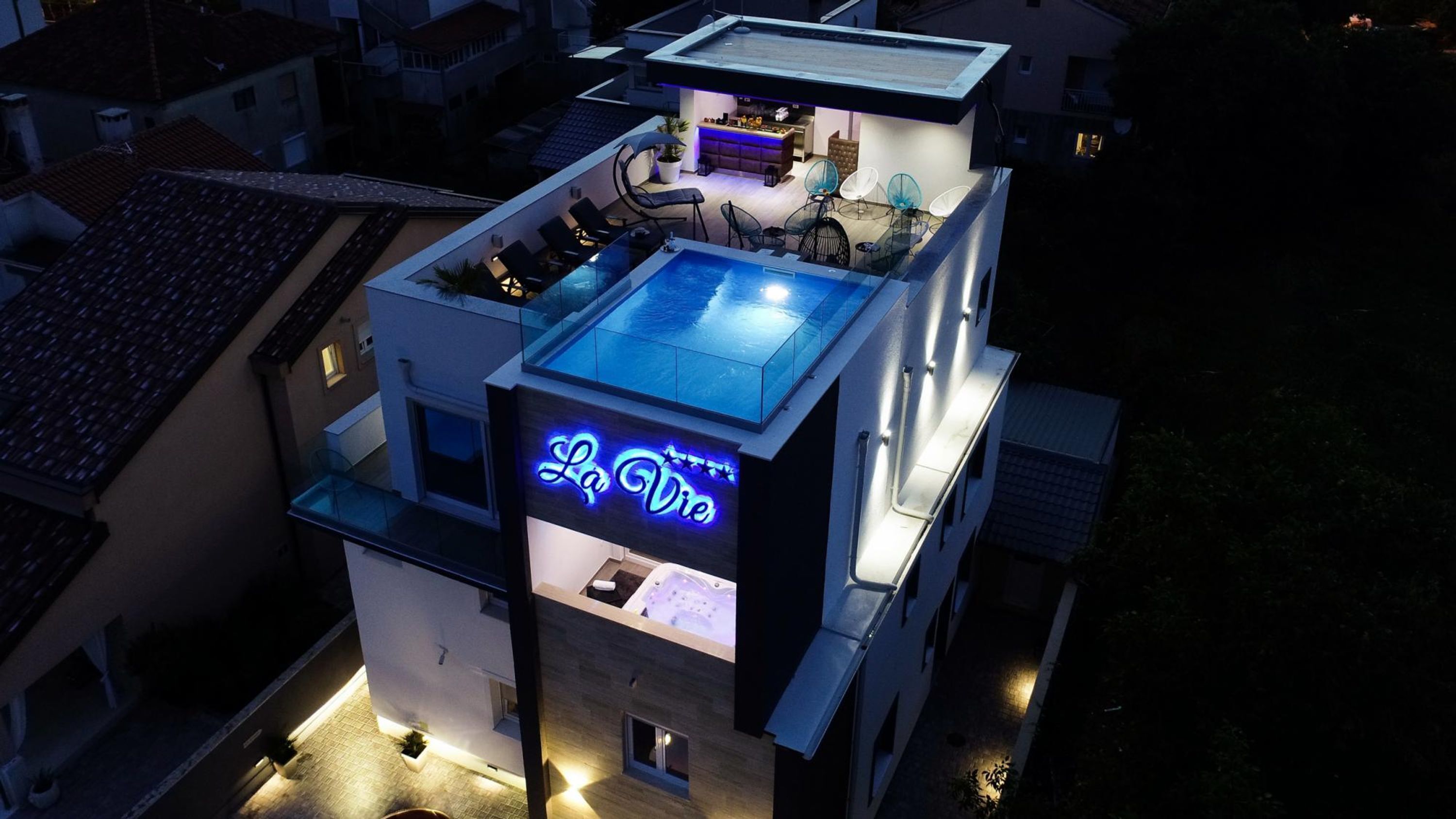 A modern building with a rooftop pool, a bar area, and a sign reading "La Vie".