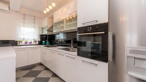 Eine moderne Küche mit weißen Schränken, einem schwarzen Backofen und einem Edelstahl-Kühlschrank.