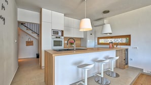 A modern kitchen with a central island, bar stools, a hanging light fixture, and a window with a view. - Villa Roberta Zadarvillas (Sveti Filip i Jakov)