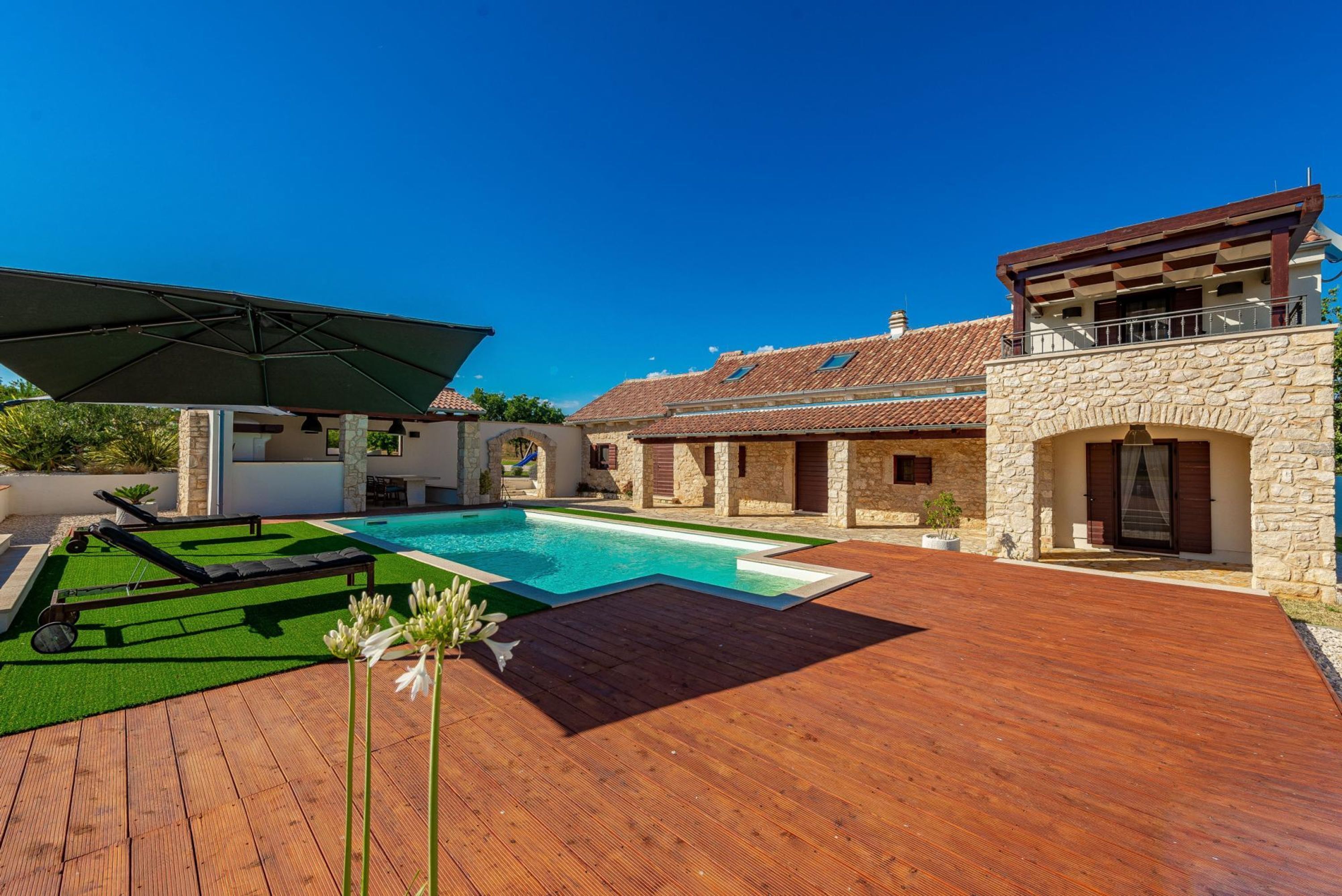 Uma villa moderna com piscina, deck de madeira e arquitetura em pedra.