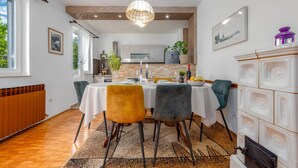 A dining area with a table set for four, a hanging light fixture, and a view of the kitchen in the background. - Villa Me Trovi Zadarvillas (Zadar)