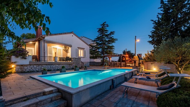 A swimming pool with steps leading up to it, surrounded by a patio area with lounge chairs and a small deck. - Villa Me Trovi Zadarvillas (Zadar)