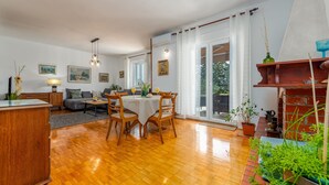 A spacious living area with a wooden floor, a dining table with chairs, a sofa, and a coffee table. There are potted plants and artwork on the walls. - Villa Me Trovi Zadarvillas (Zadar)