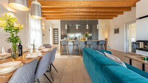 A modern kitchen with a central island, bar stools, and a teal sofa. - Villa Descansa in Dracevac Ninski (Nin)