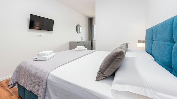 A modern hotel room with a large bed, a flat-screen TV mounted on the wall, a bedside table with a lamp, and a mirror. - Villa Descansa in Dracevac Ninski (Nin)