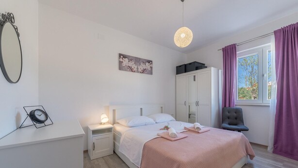 A bedroom with a bed, nightstands, a mirror, a clock, a painting, a wardrobe, and a chair. - Villa Tara Zadarvillas (Benkovac)