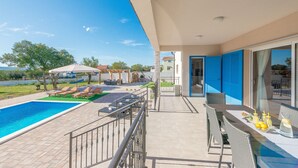 A balcony with a swimming pool, outdoor furniture, and a dining area with a table and chairs. - Villa Tara Zadarvillas (Benkovac)