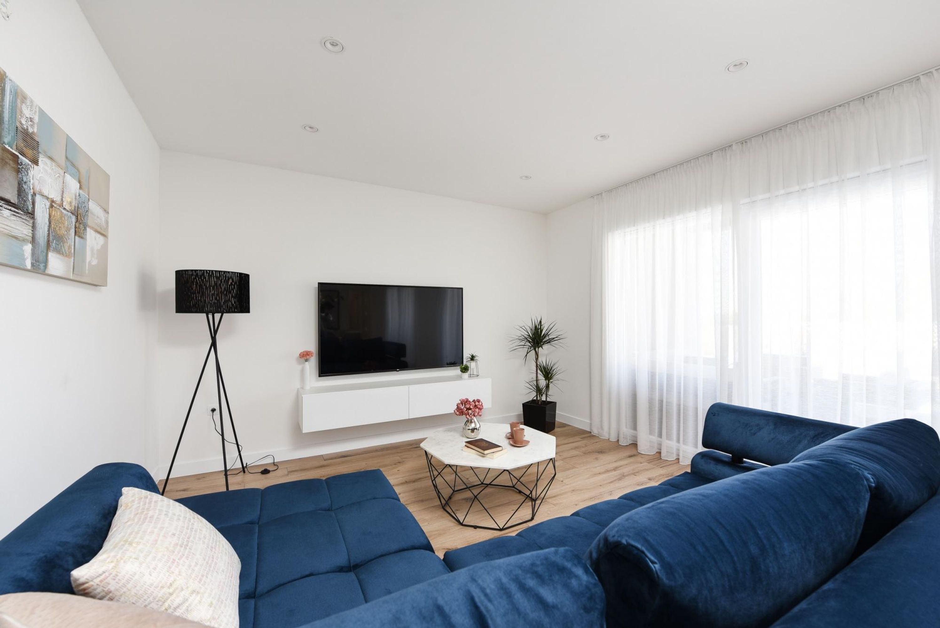 Uma sala de estar moderna com uma grande TV de tela plana, um sofá, uma mesa de centro e um abajur.