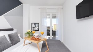 Ett modernt hotellrum med en säng, ett brickbord med frukost, en TV och utsikt över omgivningarna.