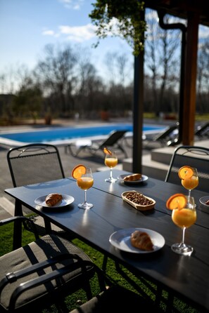 Een terras met tafels, stoelen en een zwembad op de achtergrond.