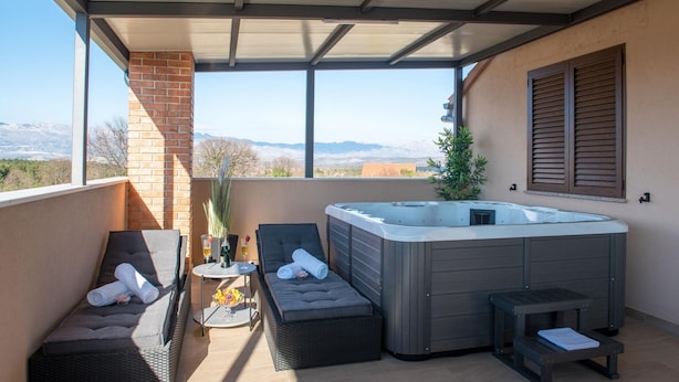 A balcony with a hot tub, seating area, and a view of mountains. - Villa Kamen Zadarvillas (Novigrad)