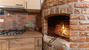 Una cocina con horno de ladrillo, armarios de madera y estufa a gas.