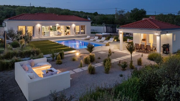 Une maison moderne dotée d’une piscine, d’un espace salon extérieur et d’un jardin bien entretenu.