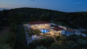 Une maison moderne dotée d’une piscine, d’un patio couvert et d’un jardin bien entretenu.