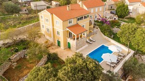Un edificio de varios pisos con piscina, mobiliario exterior y un muro de contención de piedra.