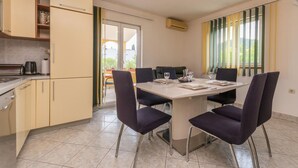 Una cocina moderna con comedor, que cuenta con una mesa grande con sillas, horno empotrado y ventana con cortinas.
