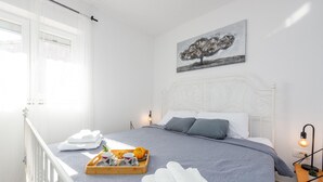 A neatly made bed with a grey bedspread, white pillows, and a tray of breakfast items. - Villa Moki Zadarvillas (Benkovac)
