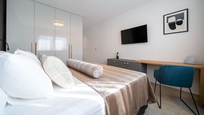 A modern bedroom with a bed, a desk, a chair, a TV, and a wardrobe. - Villa Oasis Zadarvillas (Zadar)
