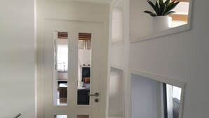 A narrow hallway with a white door, a small window, and a wooden floor.