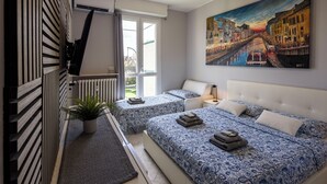 Un dormitorio moderno con dos camas, un ventanal grande y una pintura de un paisaje urbano.