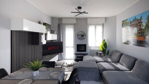 Una sala de estar moderna con un sofá, una mesa de comedor para cuatro personas, un televisor y una chimenea.