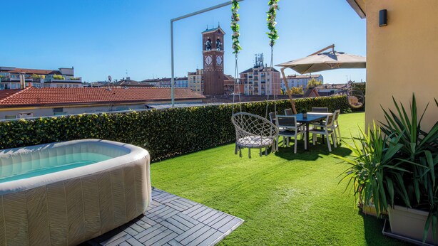 Terraza en la azotea con hidromasaje, mobiliario exterior y vistas a una torre del reloj.