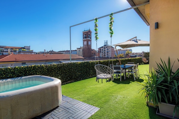 A rooftop terrace with a hot tub, outdoor furniture, and a view of a clock tower.