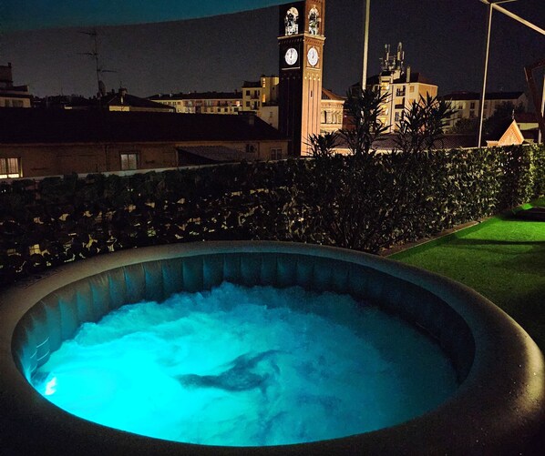 Relax in a hot tub under the stars, surrounded by a serene urban landscape.