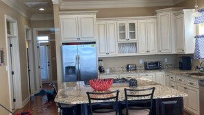 A modern kitchen with white cabinets, a granite countertop, and stainless steel appliances.