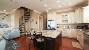 A spacious kitchen with a central island, white cabinetry, and a built-in stove.