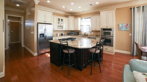A spacious kitchen with a large island, stainless steel appliances, and a dining area with a table and chairs.
