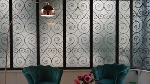 Een kamer met twee smaragdgroene fauteuils, een vloerlamp en een tafel met een bloevas.