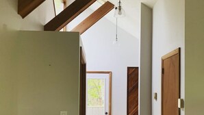 Um corredor com vigas de madeira, uma porta de madeira e um candeeiro.
