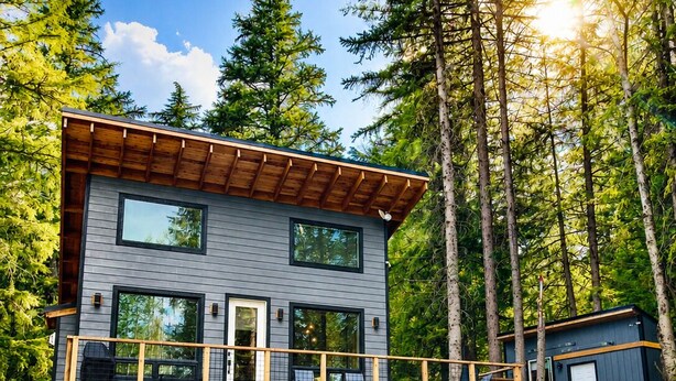 A modern two-story house with a balcony, large windows, and a garage. - Relax & Unwind: Hot Tub, Heated Garage, 3 Minutes to Village! (Sandpoint)