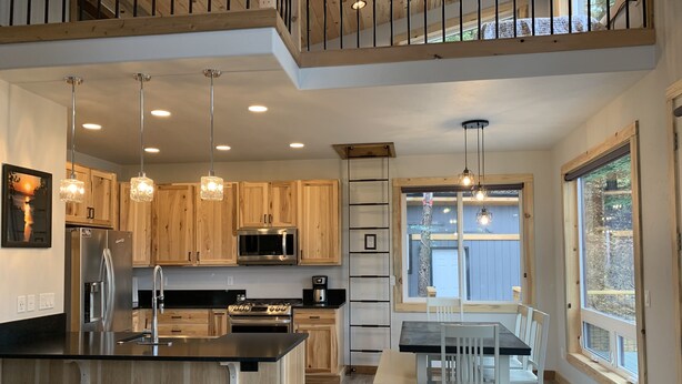 A modern kitchen with wooden cabinets, stainless steel appliances, and a central island with stools.