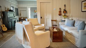 A cozy living room with a fireplace, a piano, and a dining area with a table and chairs.