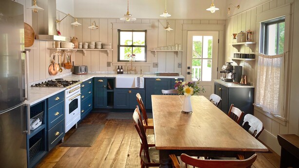 A spacious kitchen with wooden beams, a large island, and a dining area with a wooden table and chairs.