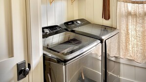 A compact kitchen with a stove, a sink, and a window with a view of a building outside.