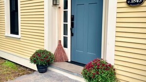 A house with a blue front door, a mailbox, and a house number plaque.