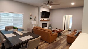 A modern living room with a dining area, a fireplace, and a TV mounted on the wall. - Beach house 3BR/3.5BA 5 minute walk to bay with extra parking for a boat/RV (Navarre)