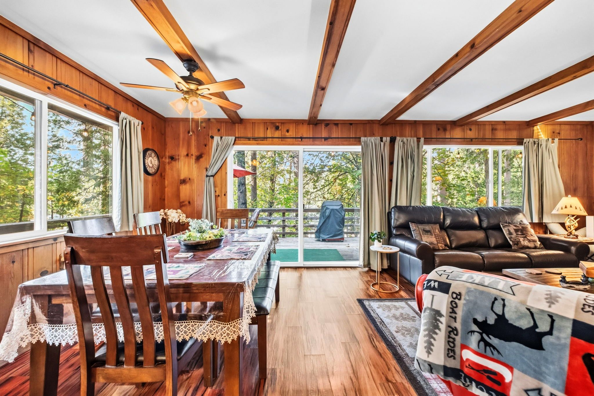 A cabin interior with a dining area, a sofa, and a ceiling fan.