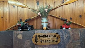 Puinen kyltti, jossa lukee ”Ponderosa Paradise”, sekä kaksi leikkukuorma-autoa, jotka on koristeltu jouluteemalla.